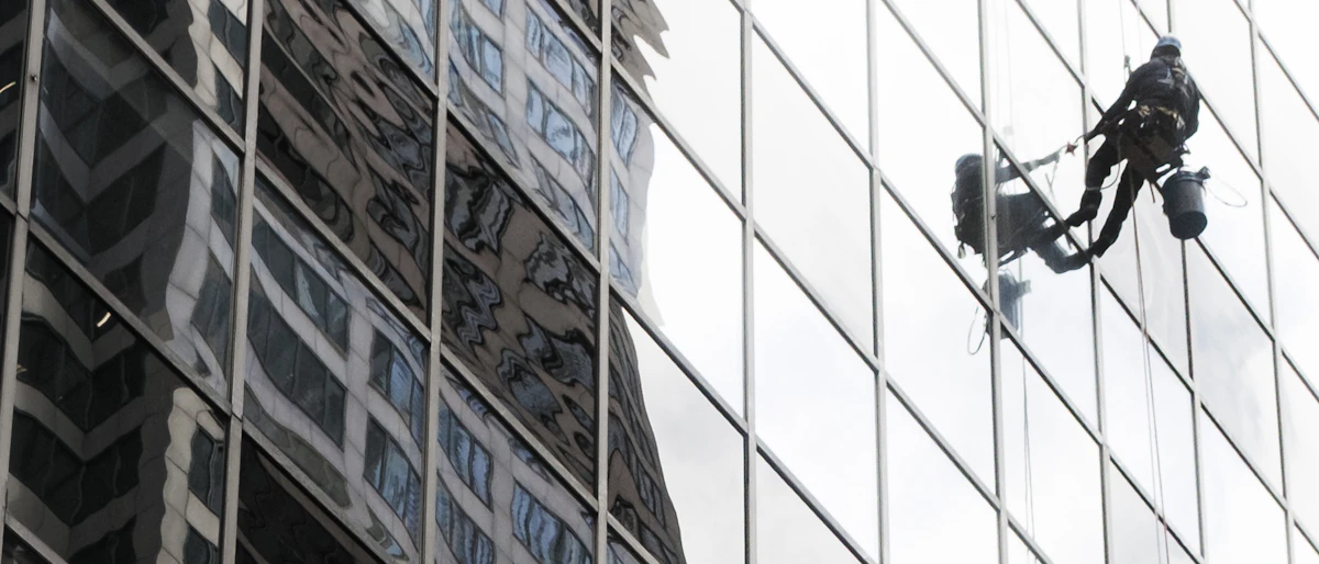 Window cleaner on rope access equipment working on a glass high-rise facade