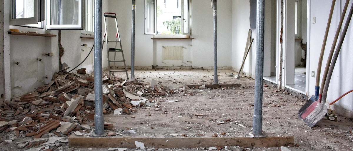 Room mid-renovation with construction dust, debris and tools on the floor