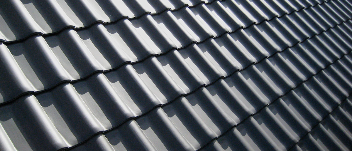 Close-up texture of dark grey roof tiles in bright sunlight